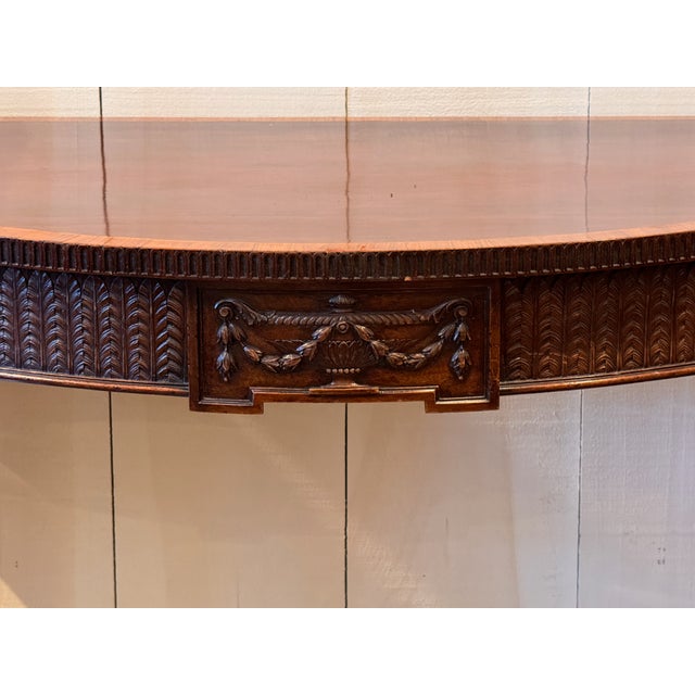 A beautifully carved mahogany server with a satinwood-banded serpentine top. The frieze is densely carved with a feather...