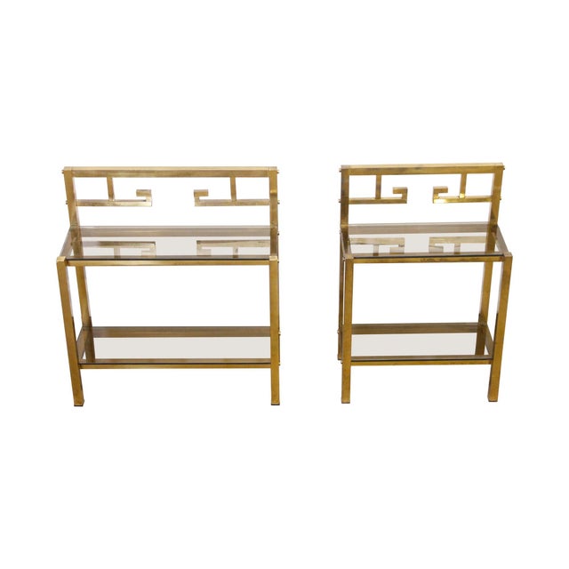 Art Deco style two tier polished brass end tables with smoked glass. One is longer than the other. Priced as a pair. The...