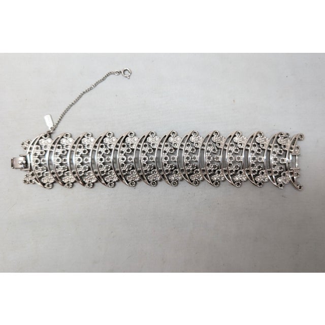 Rhodium plated wide openwork C links with circles bracelet with fold over clasp and security chain. Marked "MONET©."...