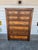 1990's vintage modern wood highboy dresser. it has four large drawers and four smaller. One drawer has different carved...