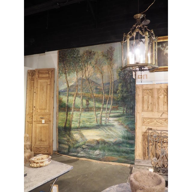 Purchased from a chateau in the South of France, this large landscape painting of a hunter walking outside of a hillside...