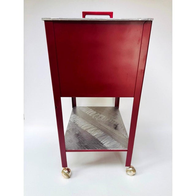 Vintage steel shop cart with a deep storage compartment, hinged lid, lower shelf and four ball casters. The silver lid and...