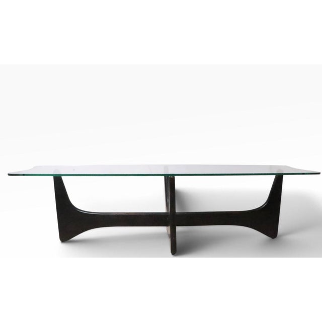 Classic Mid Century String Ray form coffee table, having a shaped glass top on a sculptural wood base. The table is in...