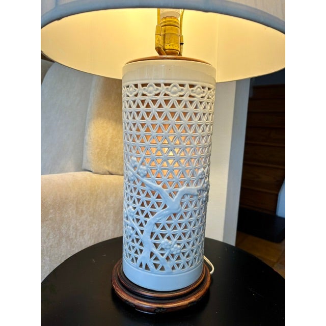 A striking mid century Hong Kong porcelain lamp featuring a white lattice body with an overlaid tree branch motif. When...