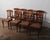 This elegant set of eight dining chairs showcases refined Neoclassical influence with graceful lines and warm cherry-toned...