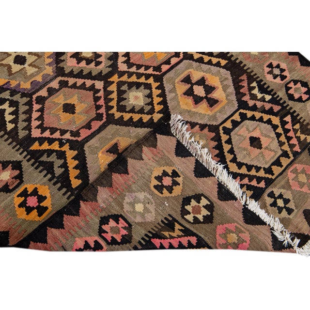 Beautiful kilim handmade wool runner with a brown field. This Vintage flatweave rug has a pink, orange, and purple accents...