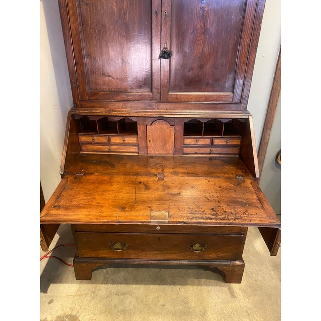 The moulded cornice above a pair of panelled cupboard doors over a fall front - with elaborated fitted interiors. Has an...