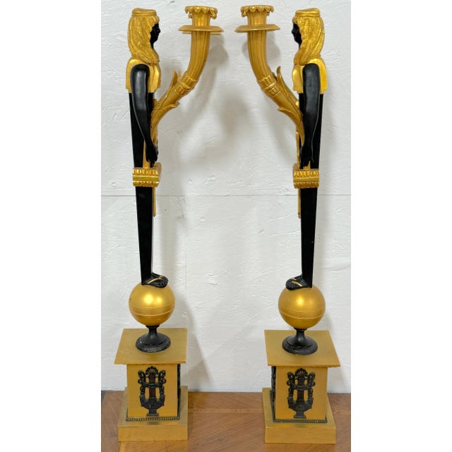 Pair of Empire-Style Egyptian Caryatid Two-Light Ormolu and Patinated Candelabra, France, 20th Century A pair of exquisite...