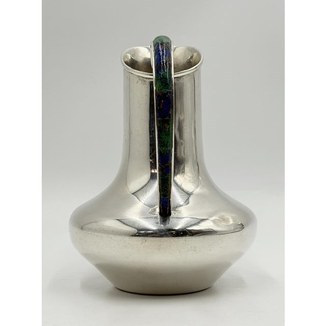 A striking vintage Mexican silver plate water pitcher by Los Castillo of Taxco, distinguished by a sculptural silhouette...