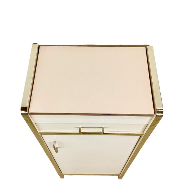 A wonderfully period 1980s jewelry armoire combining a streamlined cream laminate exterior with reflective gold-tone...