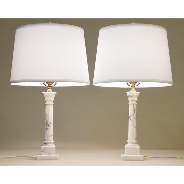 A striking matching pair of Italian Carrera marble Classic Hollywood Regency Corinthian Column style table lamps from...