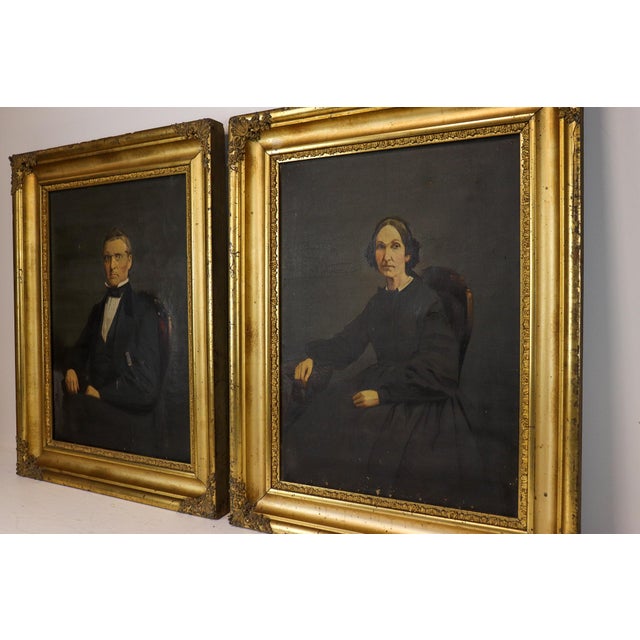 A wonderfully atmospheric pendant pair of antique Victorian oil portraits, depicting a seated gentleman and woman against...
