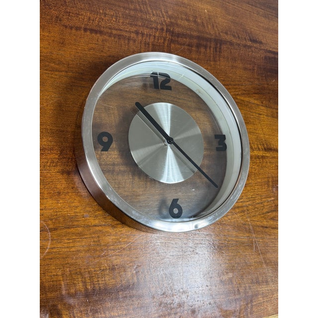 Design Plus Gallery presents a Round Wall Clock from Alivar. The circular form is framed in metal with a clear face that...