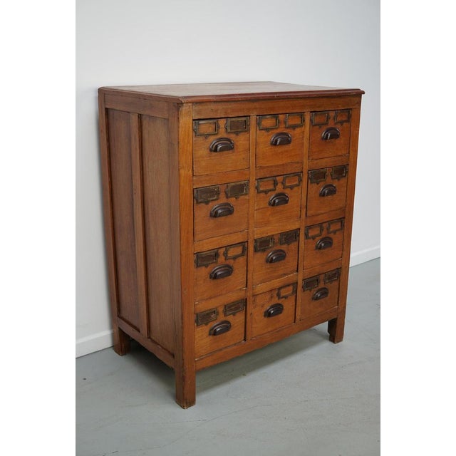 This apothecary / filing cabinet was produced during the 1930s in Indonesia. This piece features 12 drawers with brass /...