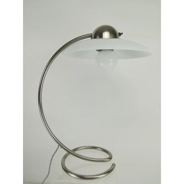 Nickel-plated brass tube with glass shade, made in Germany. Height: 48 cm Diameter of the foot: 20 cm This piece is...