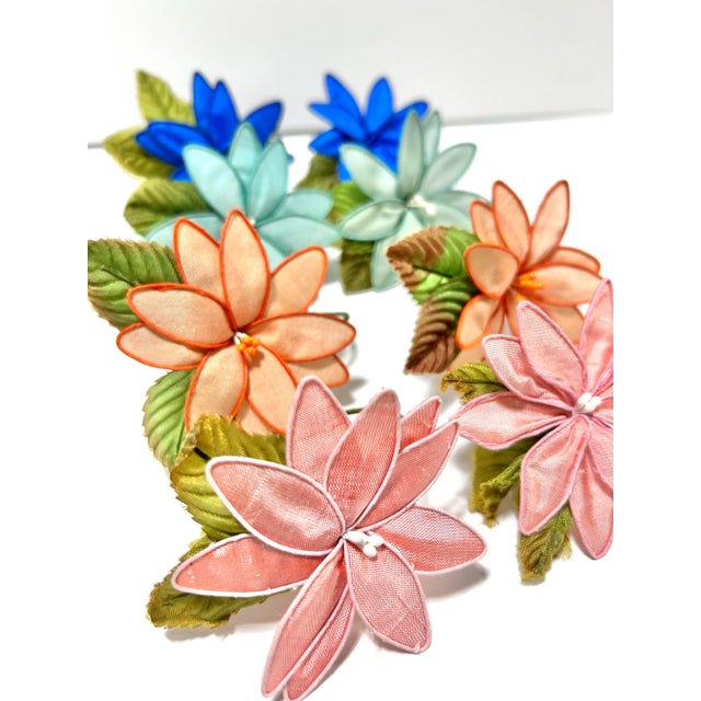 A charming set of eight handmade vintage silk flower napkin rings in a vibrant mix of pink, coral, aqua, and cobalt tones....