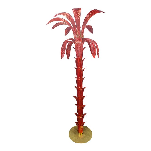 The floor lamp which reproduces the trunk and leaves of a palm tree with pieces of glass is composed of a circular base...