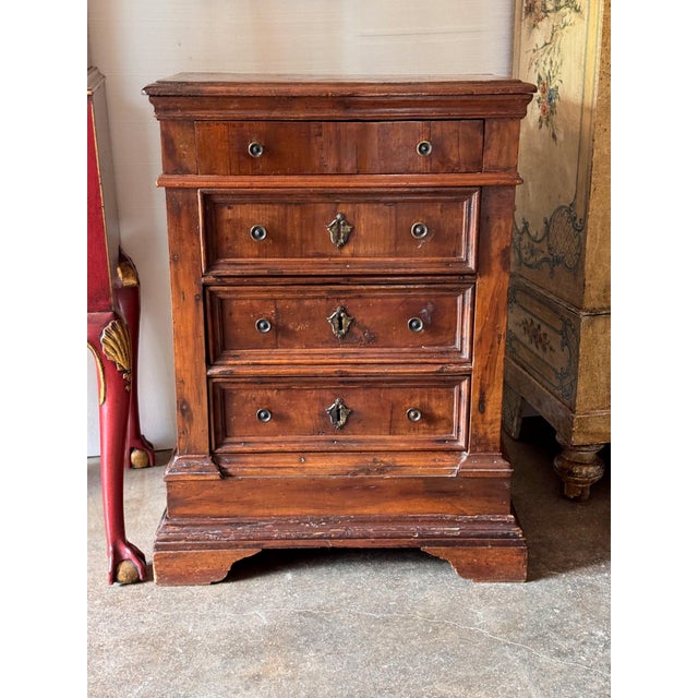 18th century Italian walnut commode of small scale, with a molded top over a slim frieze drawer and three drawers below...