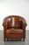 This sheepskin club armchair is crafted in a warm cognac color and finished with decorative nails. The armchair features a...