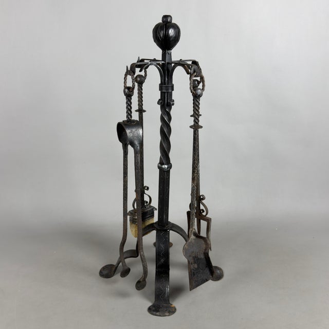 A refined and sturdy freestanding fireplace set complete with four hand-forged and wrought iron tools, a fine example of...