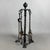 A refined and sturdy freestanding fireplace set complete with four hand-forged and wrought iron tools, a fine example of...