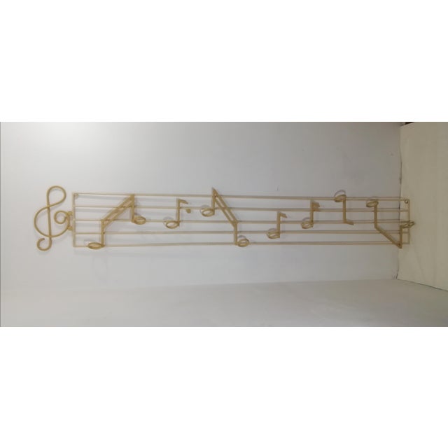 Original vintage coat hanger in heavy, painted metal. It depicts a sheet music with a treble clef and musical notes. Large...