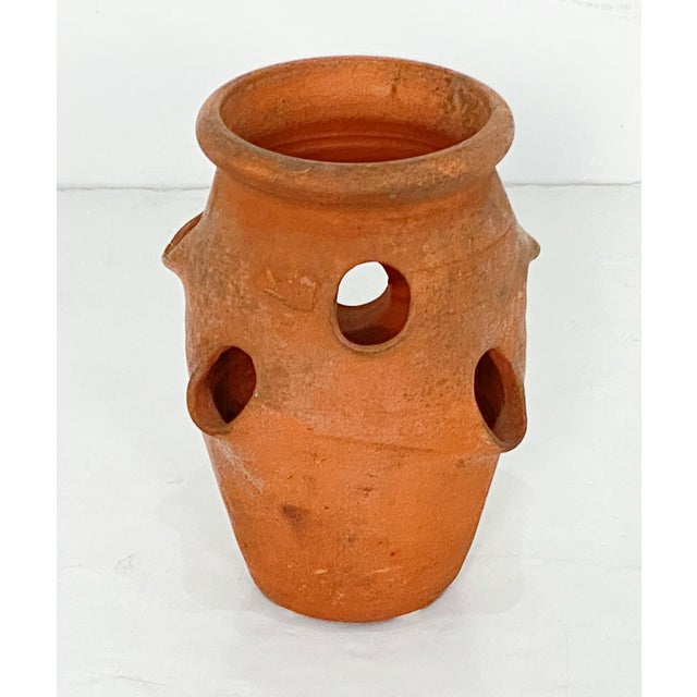 A fine vintage English round garden planter pot or urn of patinated terracotta, featuring pierced holes around the...