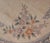 Round Chinese area rug featuring a soft ivory ground with an elaborate floral design in muted shades of dusty rose,...