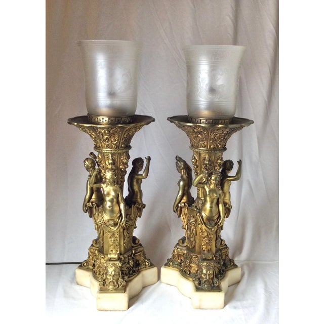 A pair of gilt bronze figural neoclassical lamps with marble bases. The bronzes with gilt surface showing wear but...