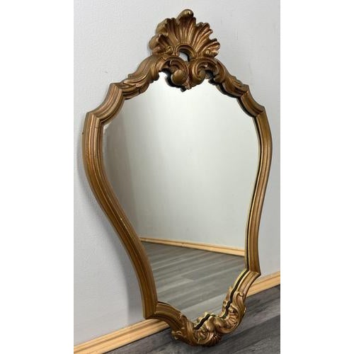 This decorative Vintage French wall mirror features an ornate shaped frame with flowing curves and classic French scroll...