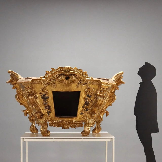 cA trapezoidal, inverted truncated pyramid structure rests on four curved feet carved with scrolls and leaves, as do the...