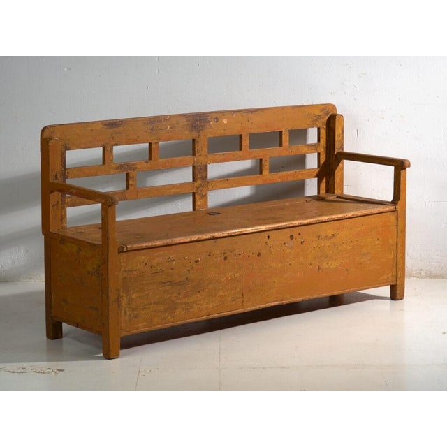 This antique painted storage bench in pine wood is a bench with storage, a lift-up seat and a lattice back, with armrests....