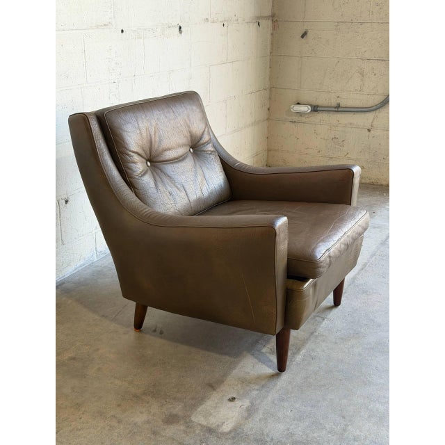 This lounge chair features a contoured frame with button-tufted backrest and sweeping armrests. Its inviting silhouette...