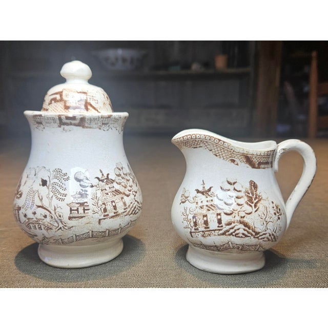This gorgeous, unmarked sugar and creamer set in the “Willow Tree” pattern is crafted from fine English hard paste...