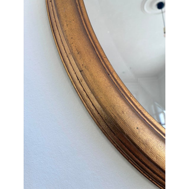 Elegant vintage oval mirror from Belgium, with beveled glass and a carved giltwood frame in a soft gold finish. Object:...