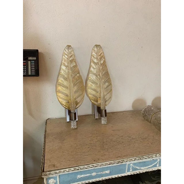 Beautiful pair of large scale Murano glass leaf form sconces by Bavovier and Toso. The clear glass with flecks of gold. A...