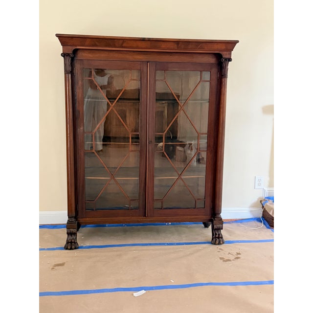 Antique Empire Cabinet A beautiful antique American Empire glass front bookcase with carved columns and lion paw feet....