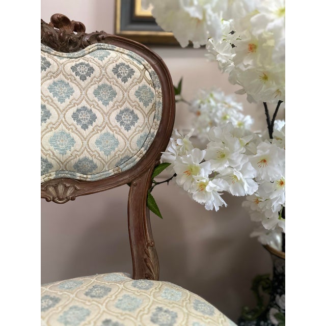 An elegant pair of early 19th century French salon chairs, distinguished by their shaped backs, finely carved aprons, and...