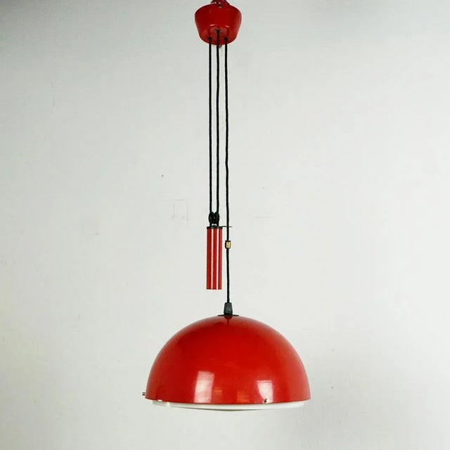 This charming Red lacquered Midcentury Modern pendant lamp with counterweight has been designed and produced in Italy in...
