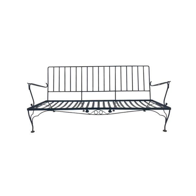 Classic four-piece wrought iron garden set, attributed to Woodard, includes a three-seat sofa, a stationary lounge chair,...