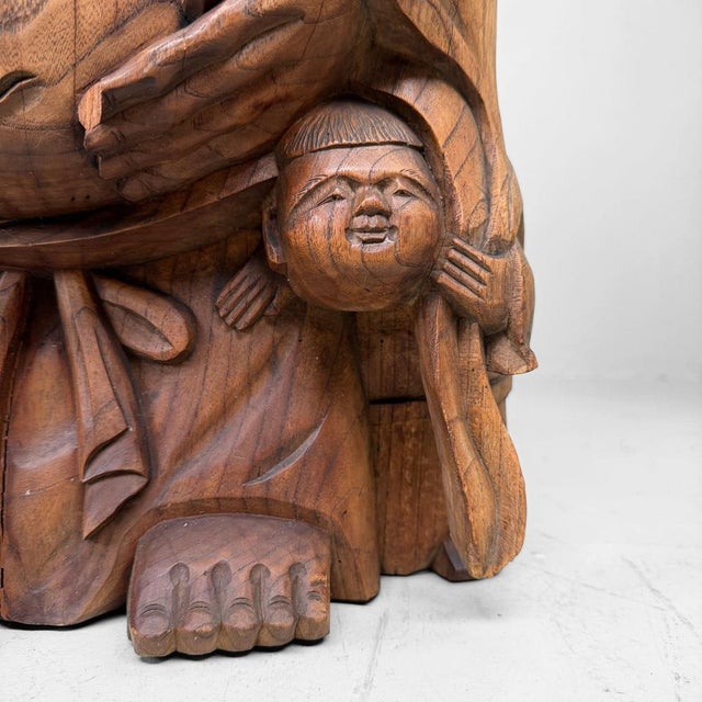 A large Japanese statue of Hotei, the laughing god of good fortune from the Shichifukujin tradition, with a small child...