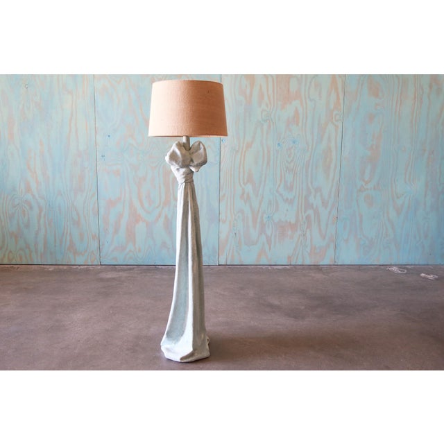 A heavy plaster floor lamp featuring a Trompe l'Oeil design that mimics the elegance of knotted, draped fabric. Finished...