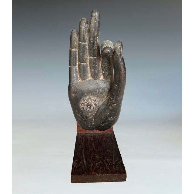 A bronze buddha hand sculpture mounted on a wood base. The last photo shows two nails in-between the wood and bronze hand....