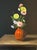 Oil painting on canvas board of yellow and pink daisies and roses in an orange vase set on a table by Satori Gregorakis....