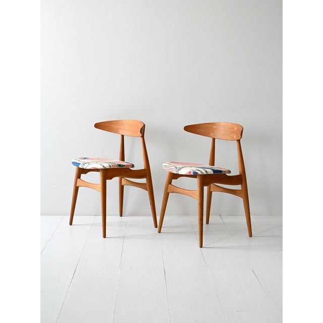 Iconic 1950s Danish chairs with oak frames and seats upholstered in Josef Frank's signature fabric. Pair of CH33 chairs...