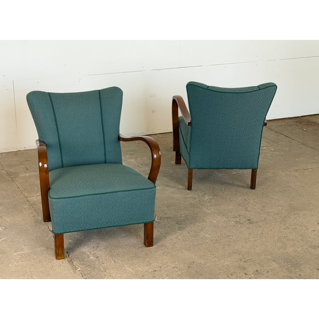 A pair of Danish lounge chairs with open bentwood armrests, Denmark, 1940s. The backrest rises to a softly flared upper...