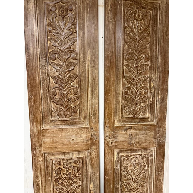 A striking pair of narrow arched door panels, hand-carved in an antique style with an intricate floral motif running the...