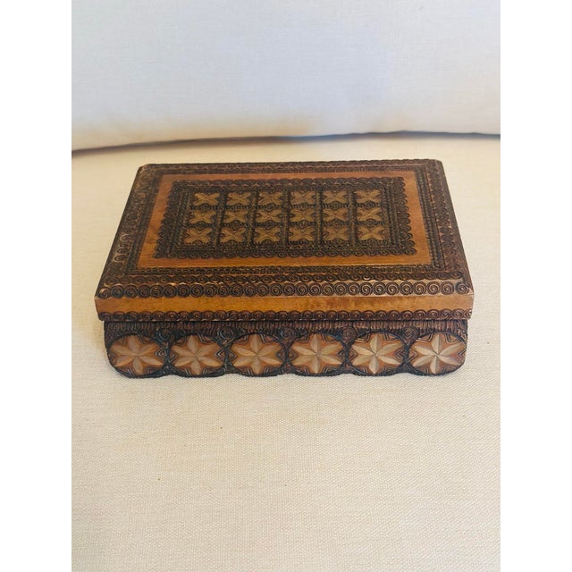 A beautifully hand-carved wooden keepsake box featuring intricate geometric and floral motifs accented by delicate...