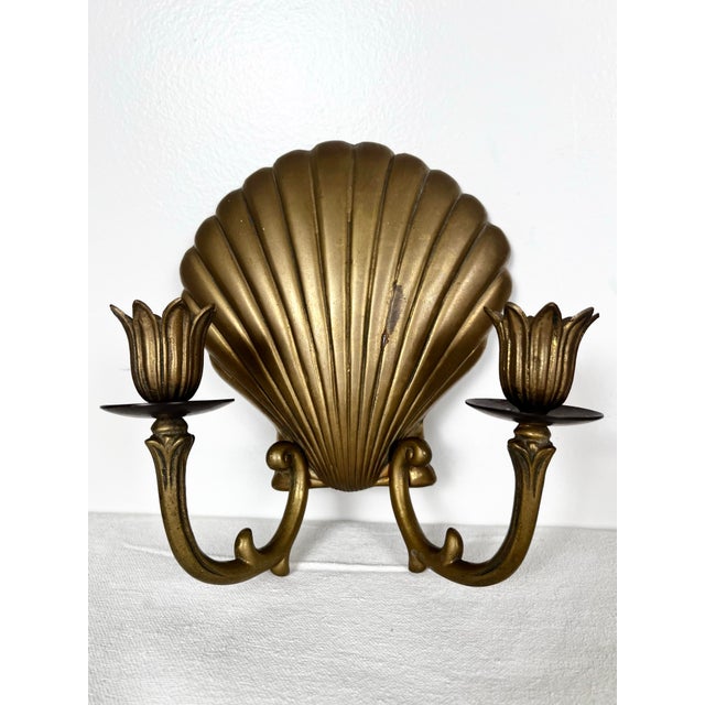 Vintage pair of brass shell candle sconces. Brass scallop shells with 2 candelabra arms each to hold candlesticks.