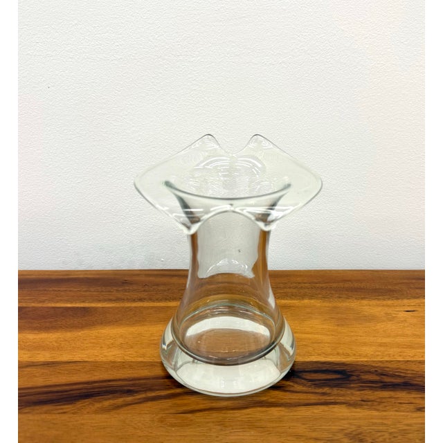 An elegant vintage hand-blown art glass vase featuring a graceful hourglass silhouette, a thick clear glass base, and a...